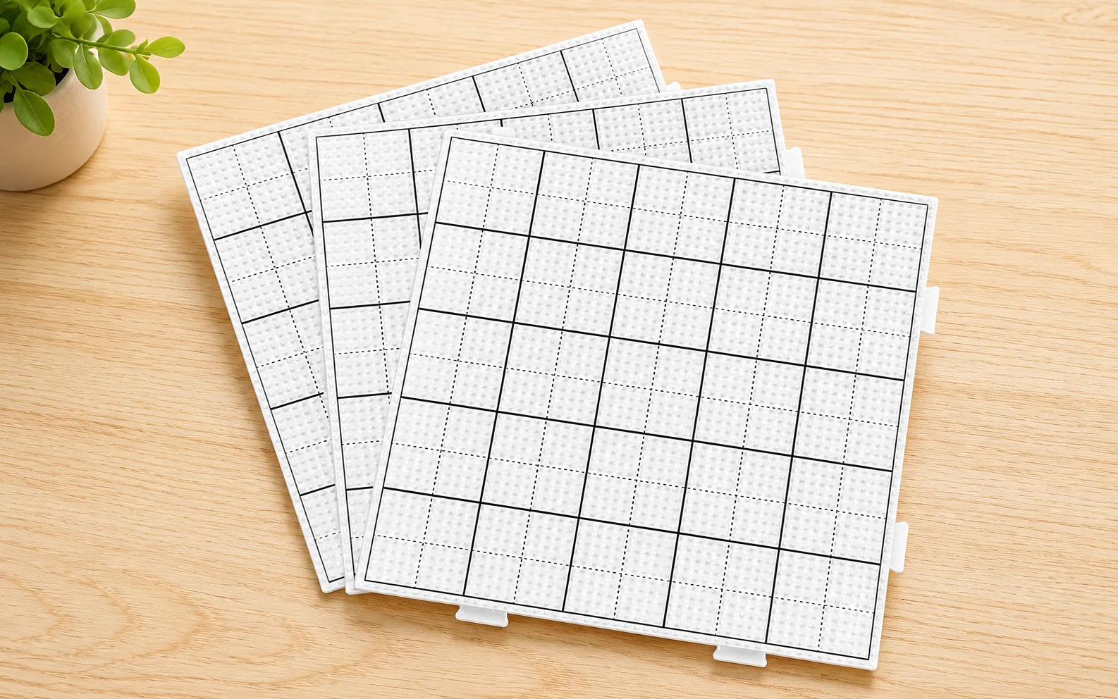 Square interlocking fuse bead pegboards with grid guide lines on a wooden table