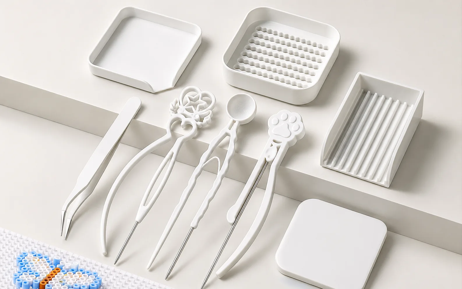 Fuse bead tweezers, bead scoops and sorting trays arranged on a work surface